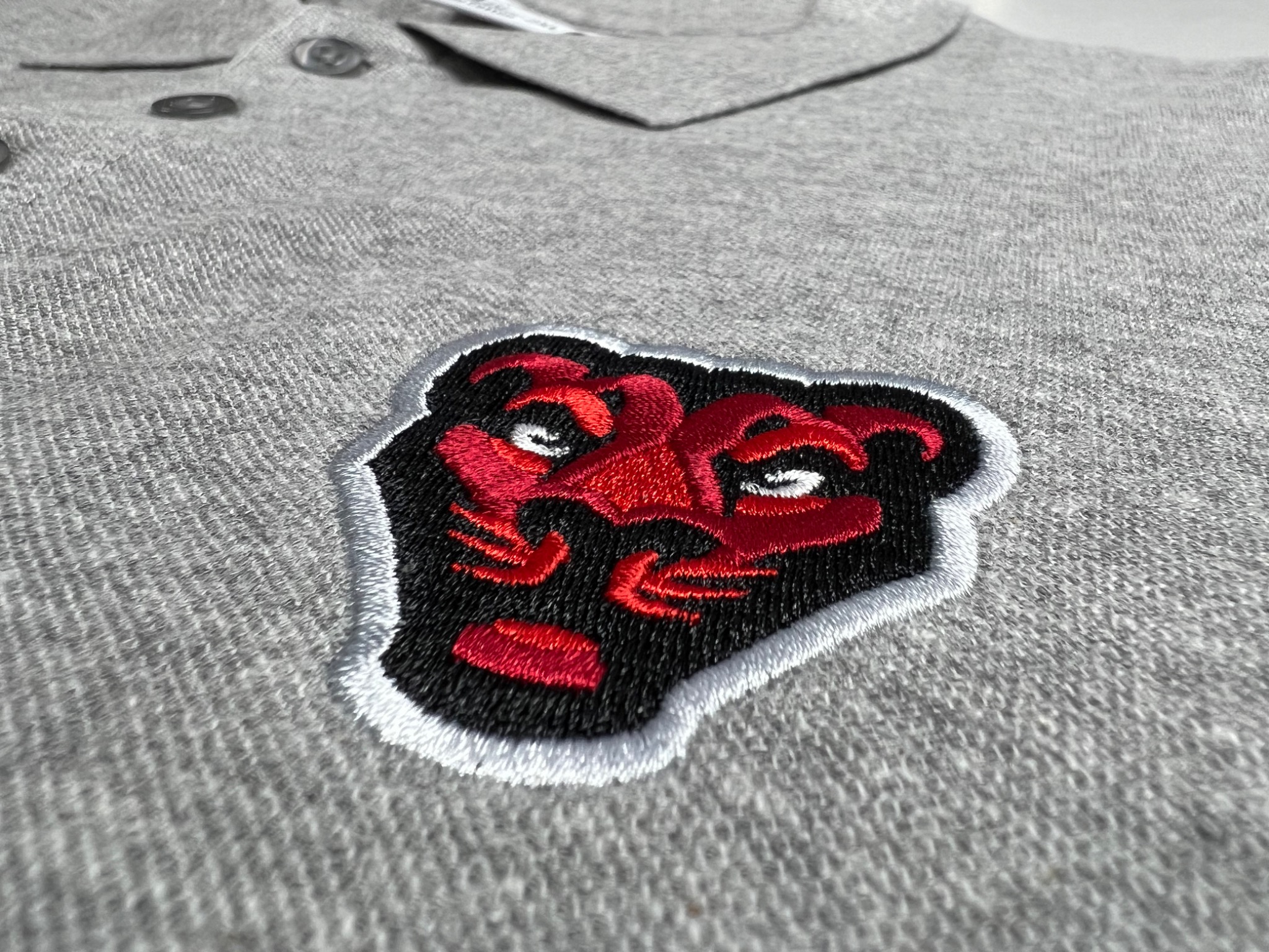 Geborduurd embleem op grijze polo